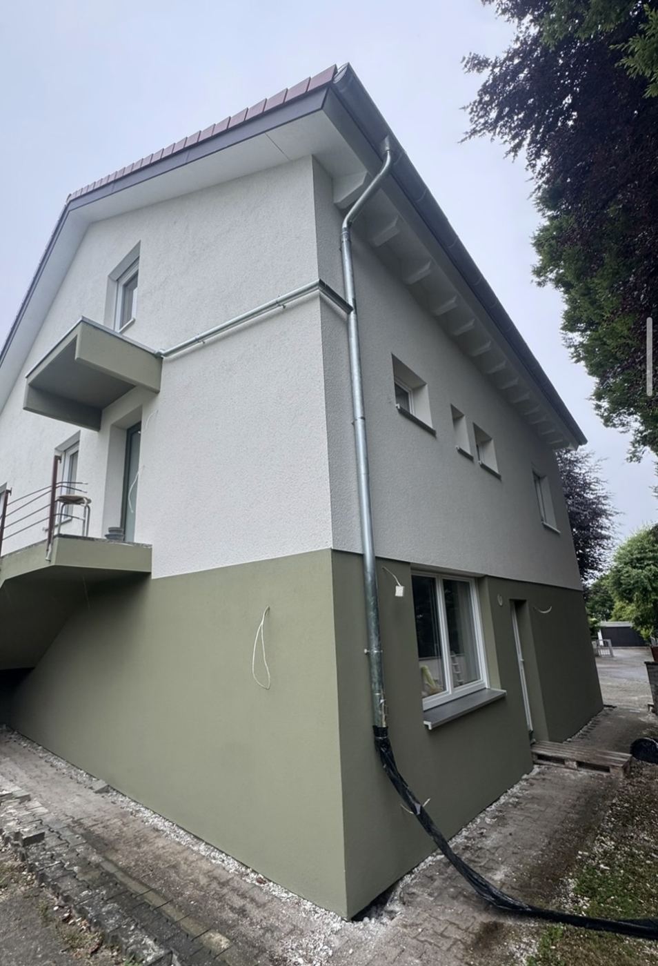 Fassadensanierung am Wohnhaus: Neuer Putz und zweifarbiger Anstrich mit abgesetztem Sockel.