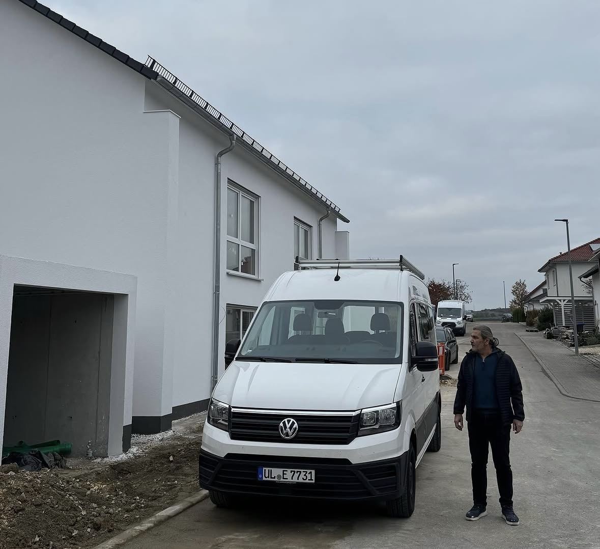 Mehmet Erdoğan vor einem fertig verputzten Neubau mit dem Firmenwagen
